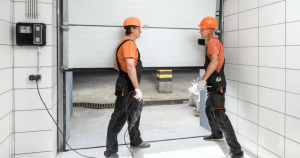 Two workers with tools in a garage.