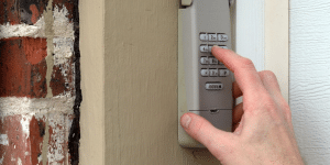 Hand enters code on garage keypad box.